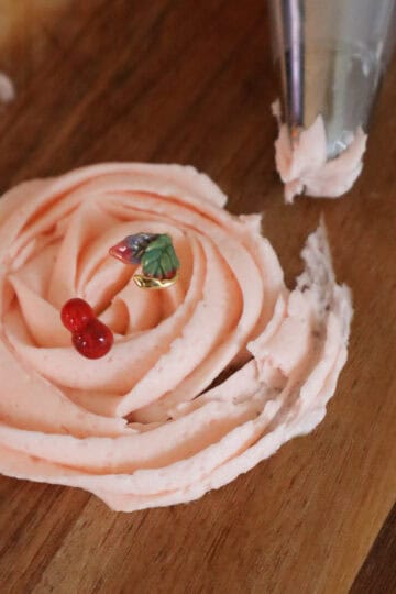pink cherry frosting piped into a rosette with a cherry ring on display